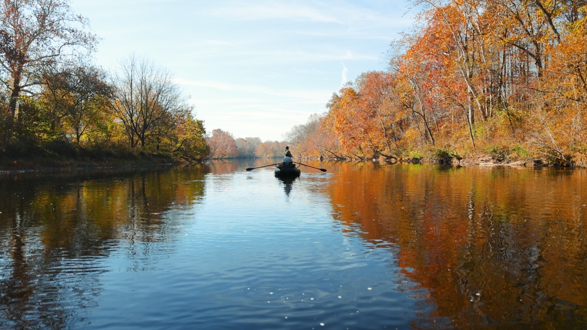 boat-going-down-river-fall-coloured-rees-all-around