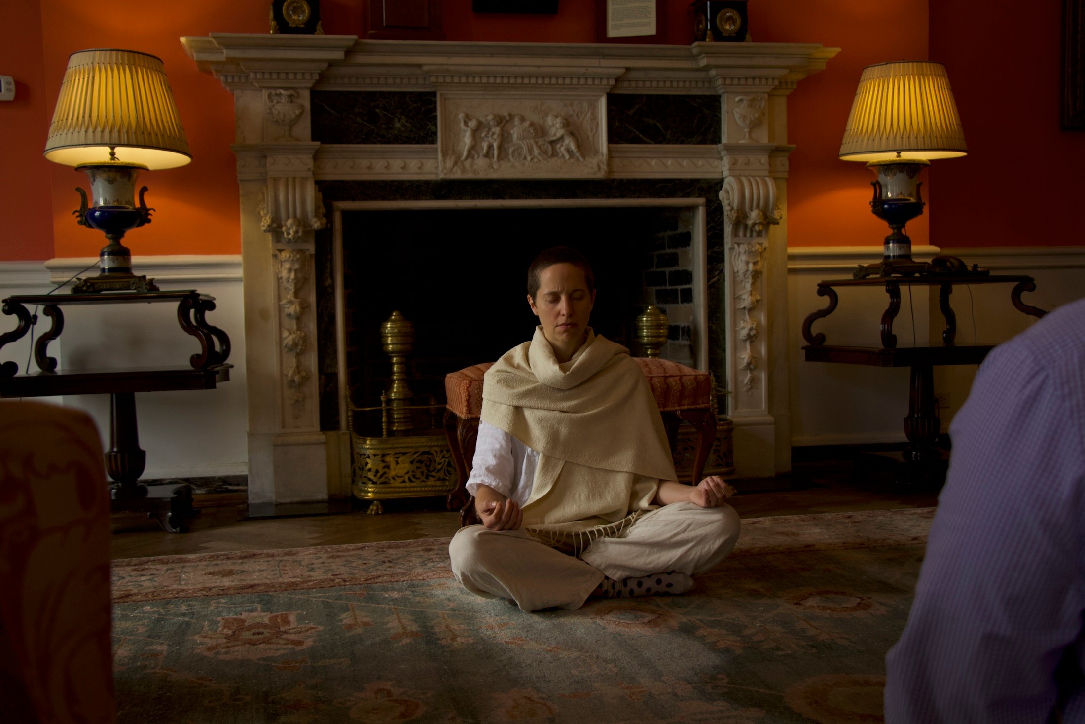 person-leading-guided-meditation-in-front-of-a-fireplace