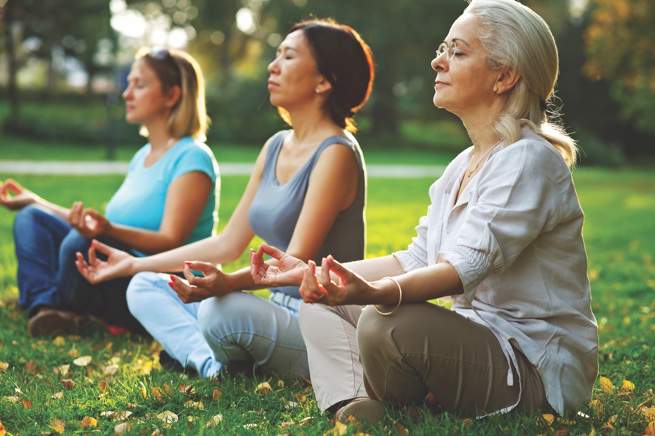 three-ladies-meditate-while-sitting-on-the-grass